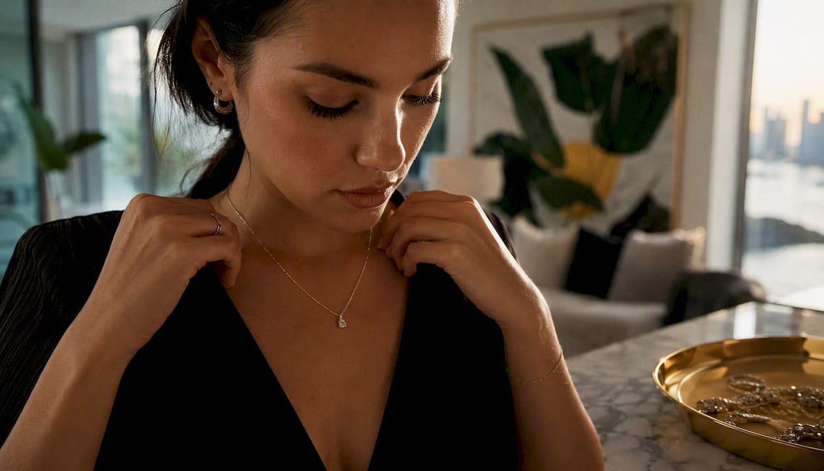 Woman adjusting silver pendant necklace on collarbone