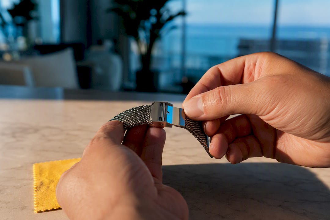 Hands adjusting an anonymous mesh watch clasp