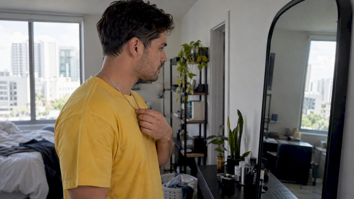 Man checking where his necklace chain sits