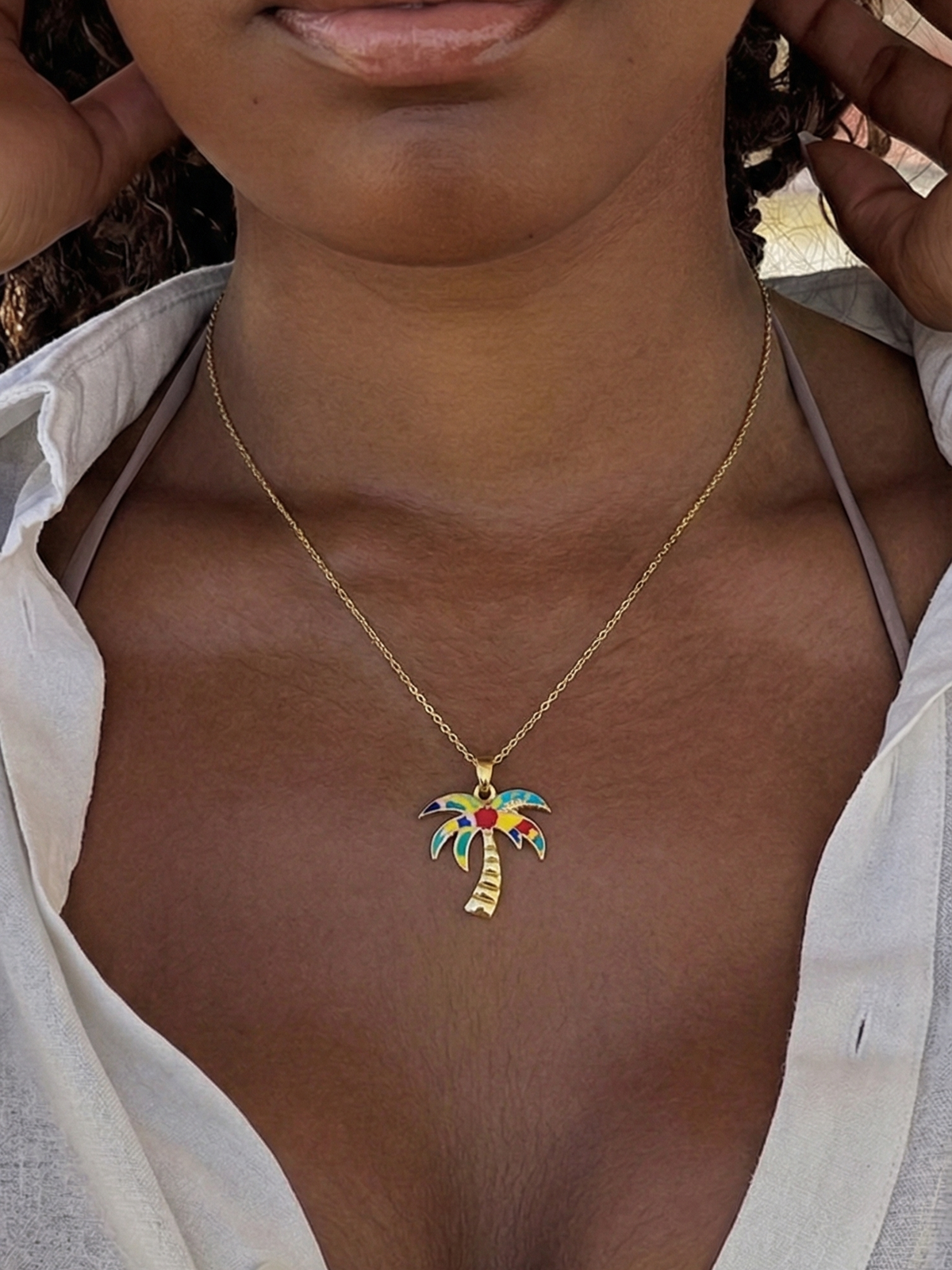 Close-up of a woman wearing the WYNWOOD BLVD Painted Gold Palm Tree Charm necklace inspired by Miami.
