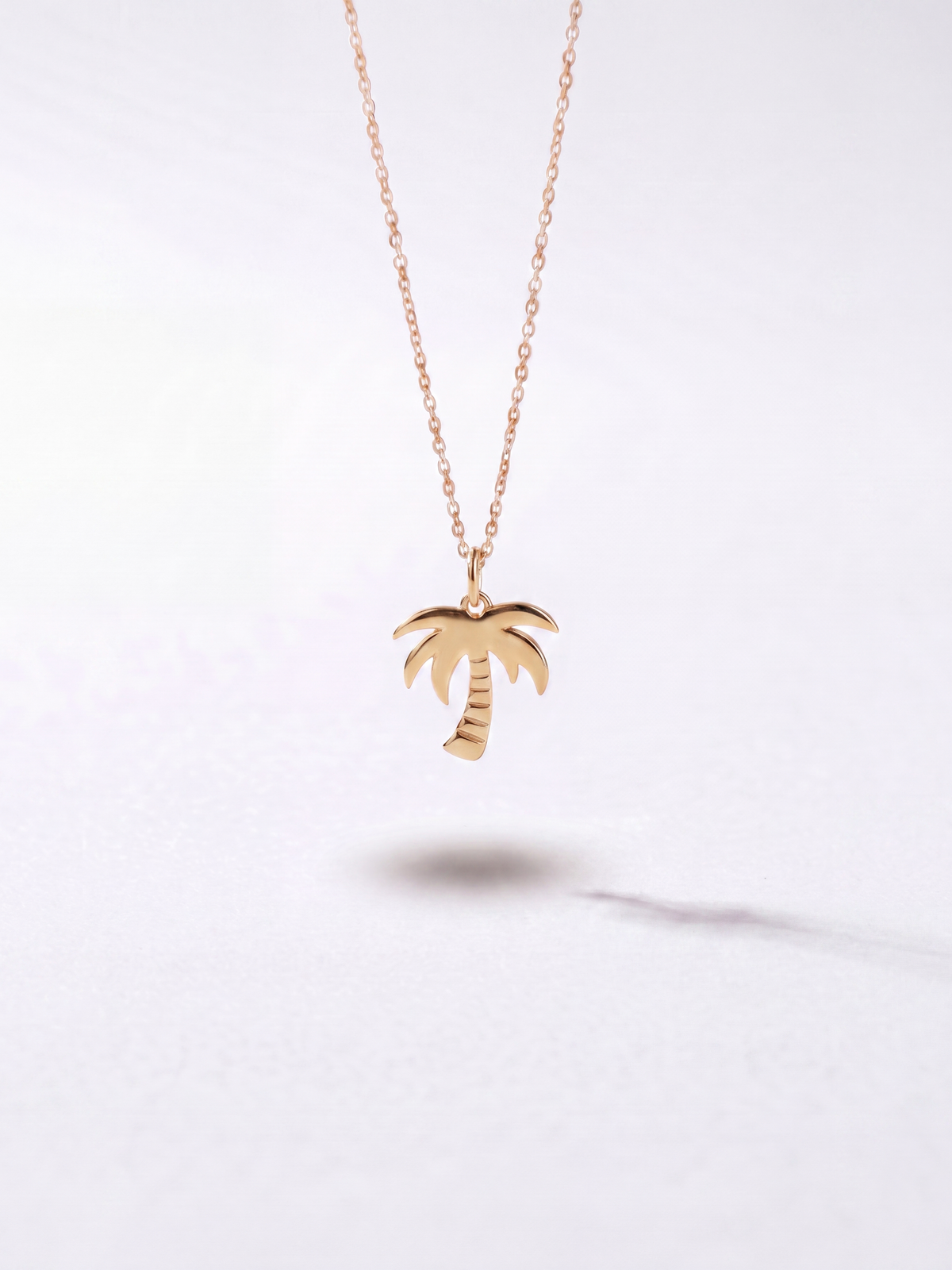 Gold palm tree pendant necklace by WYNWOOD BLVD on a clean white background.