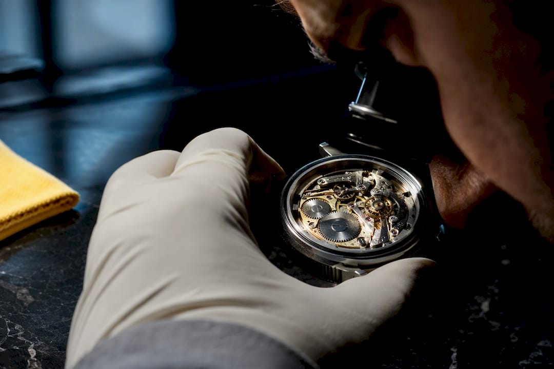 Watchmaker inspecting an exposed mechanical movement