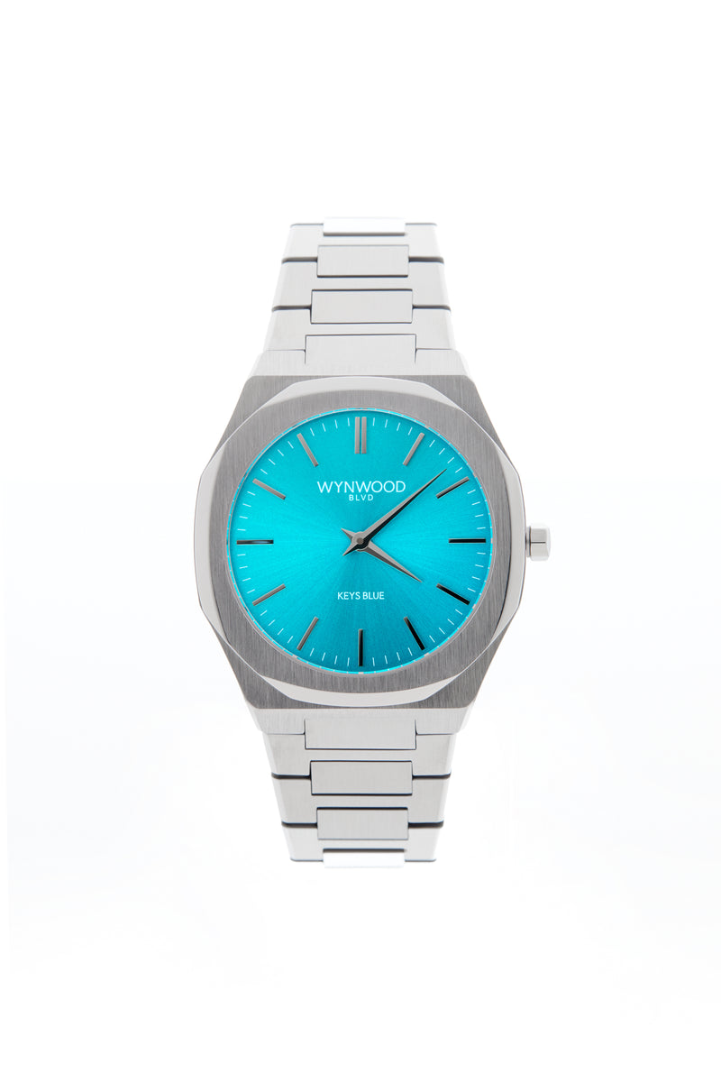 Front view of the WYNWOOD BLVD Keys Blue watch featuring a stainless steel bracelet and vibrant turquoise blue dial on a clean white background.