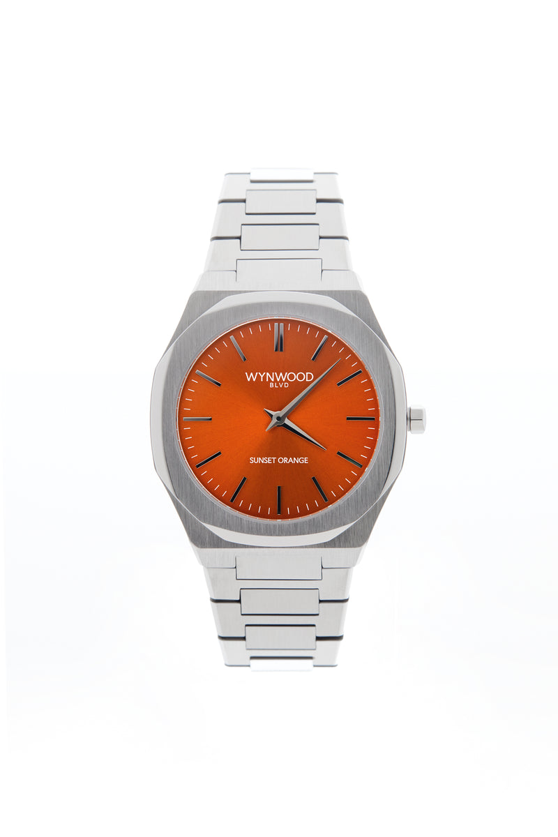 Front view of the WYNWOOD BLVD Sunset Orange watch featuring a stainless steel bracelet and vibrant orange dial on a clean white background.