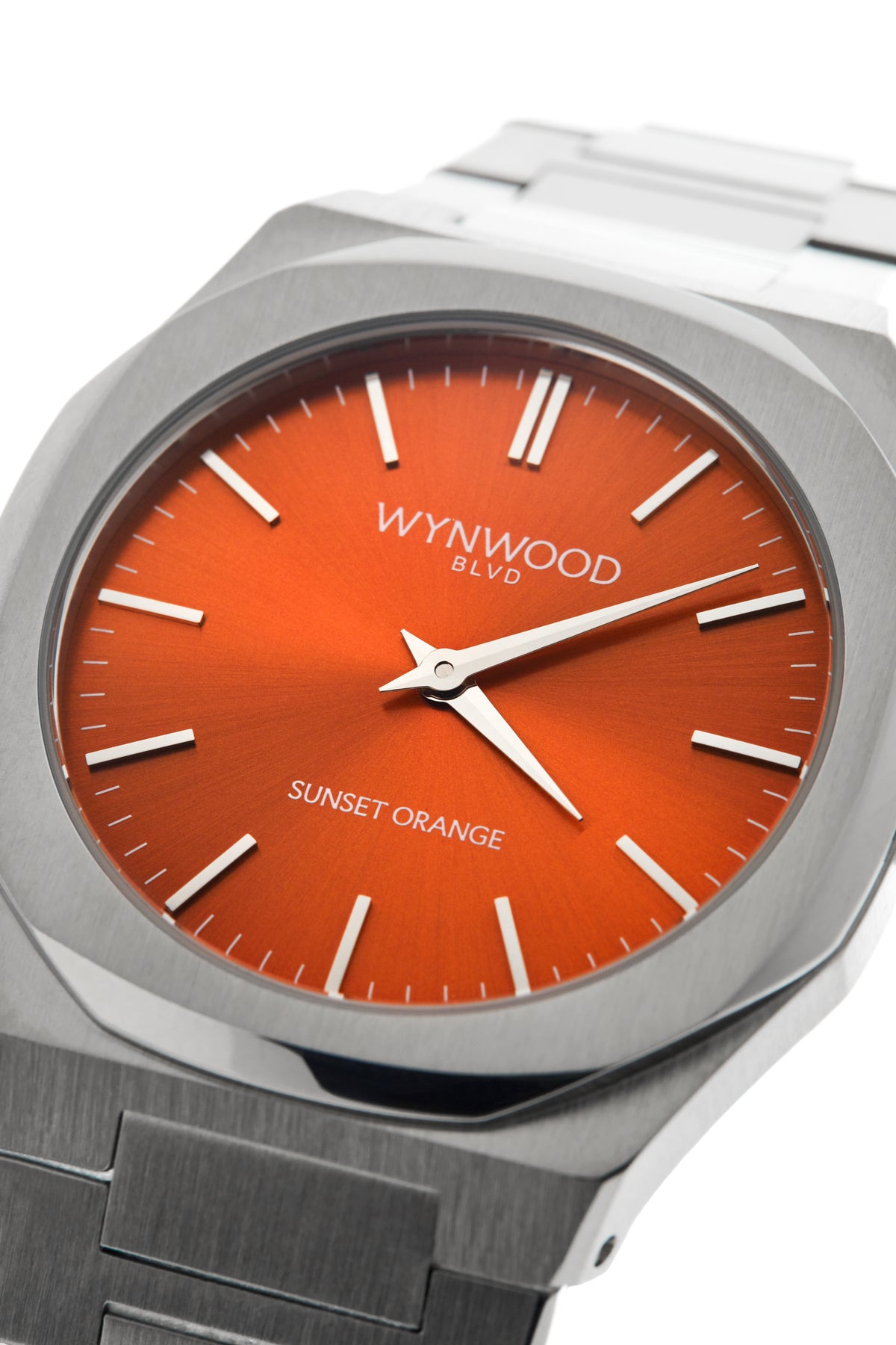 Three-quarter close-up of the WYNWOOD BLVD Sunset Orange watch featuring a brushed stainless steel case and vibrant orange dial.